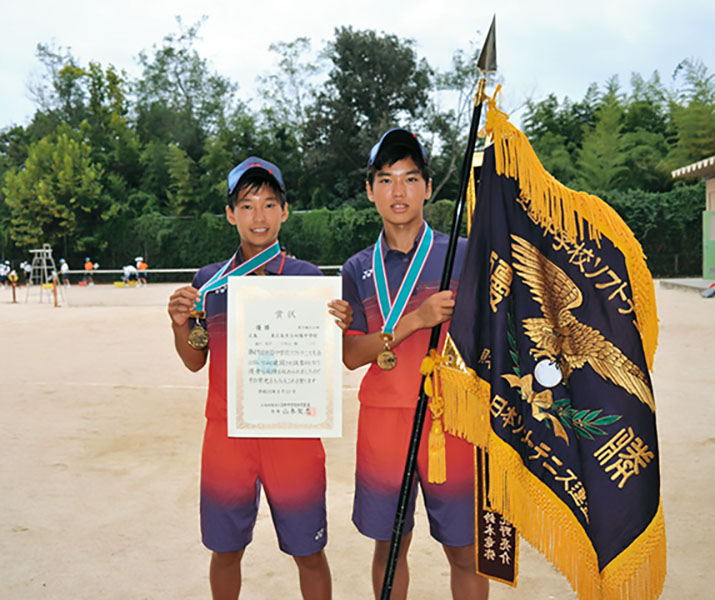 少年男子二人がソフトt寝椅子全国中学生ソフトテニス大会の優勝旗を持っている写真