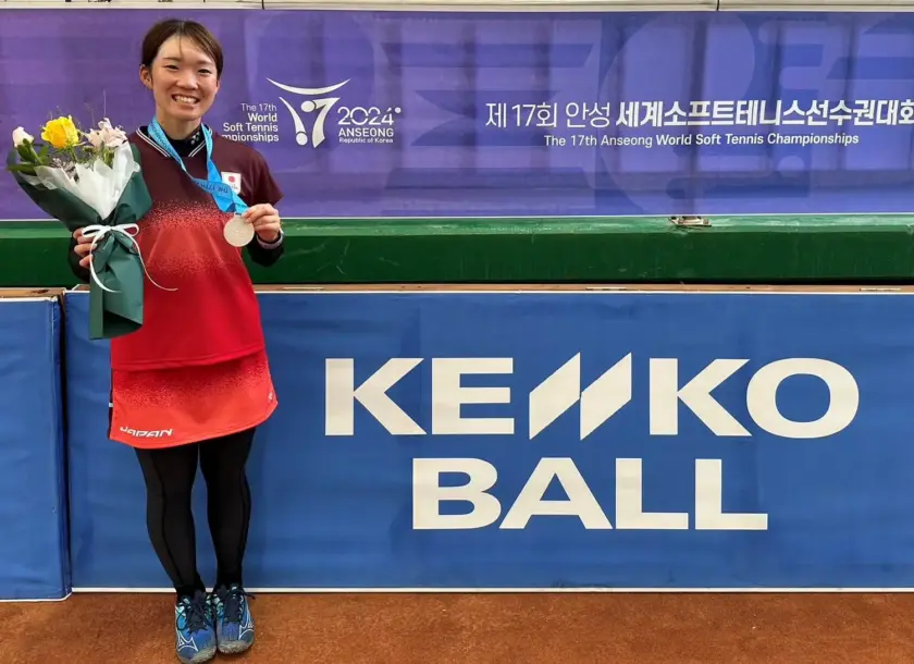 ソフトテニス女性選手がメダルと花を持っている写真