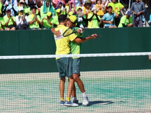 男性二人がテニスコートで喜びを分かち合っている