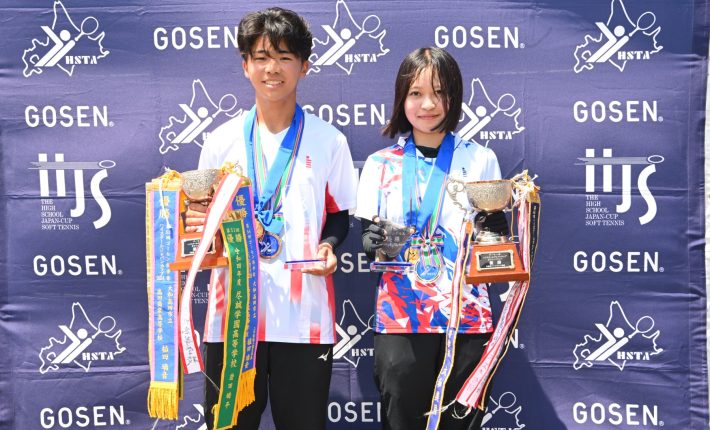 男女一人ずつトロフィーを持っている写真